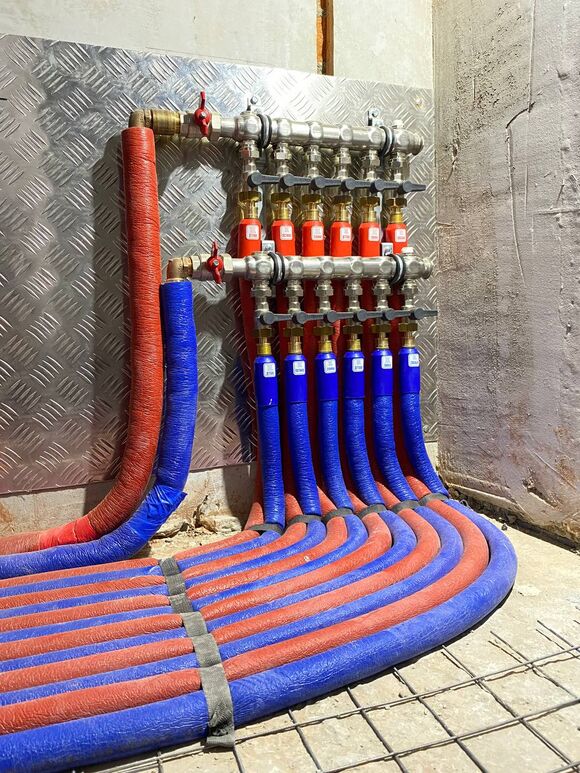 Монтаж распределительного коллекторного узла (гребенка). На каждом выходе установлены небольшие краны с черными ручками. Они позволяют перекрывать или регулировать подачу воды в каждый отдельный контур (например, в конкретную комнату или к радиатору).