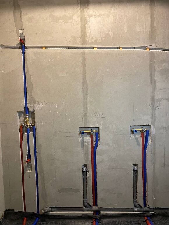 Монтаж водорозеток и скрытой разводки труб водоснабжения в санузле. Трубы уложены в заранее подготовленные штробы (каналы в стене), которые впоследствии будут заделаны и облицованы плиткой.