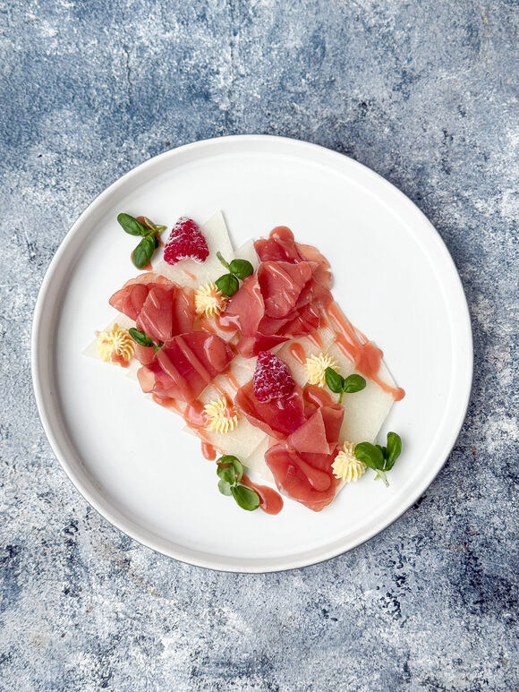 <p>Карпаччо из дыни с прошутто, свежей малиной и соусом из маракуйи</p>